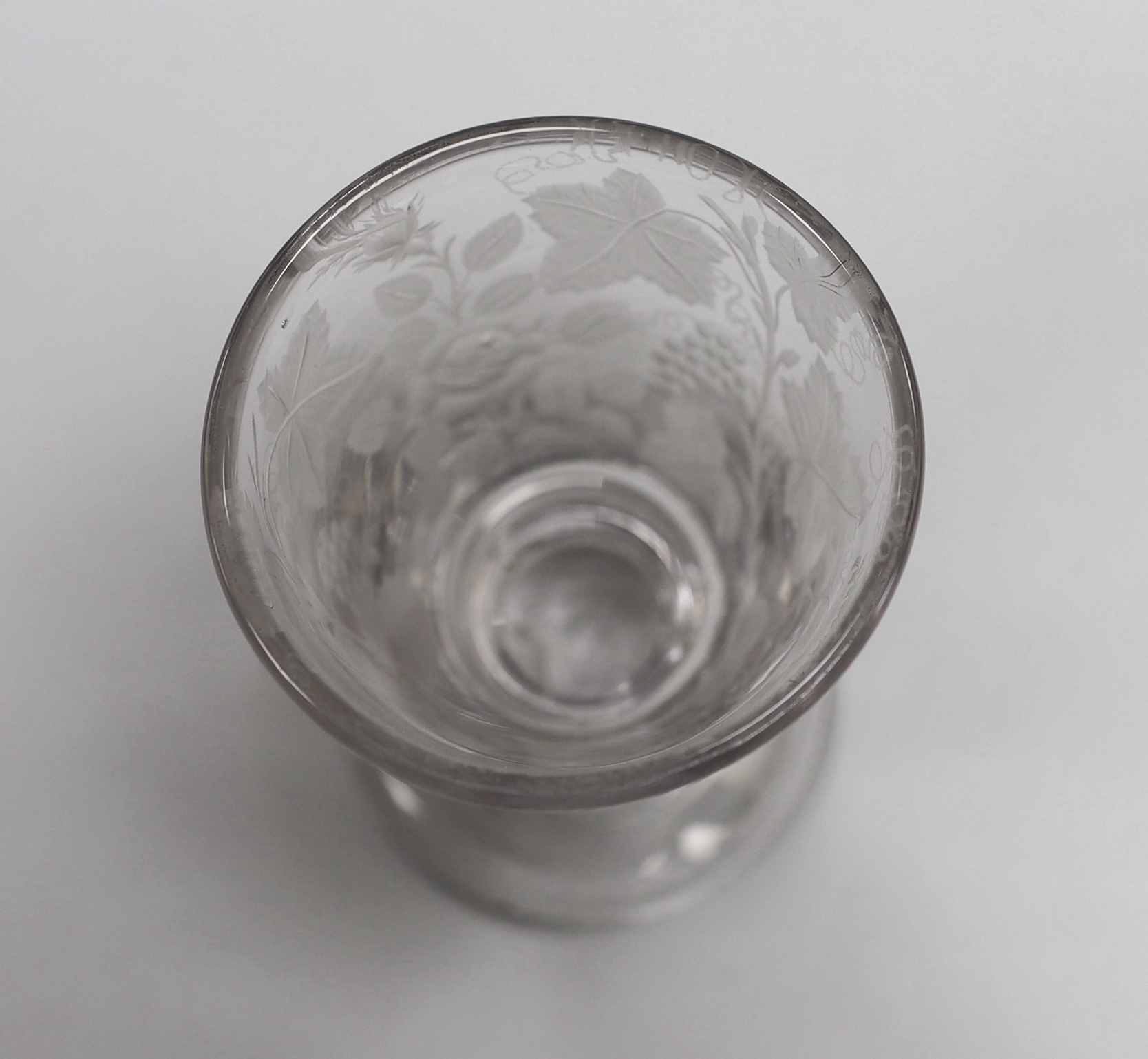 An English lead crystal engraved goblet/rummer, c.1800, bucket bowl, engraved with fruiting vines, a rose and scripted initials, possibly ‘JAB’ or ‘TAB’, capstan stem and plain foot with rough pontil, 13.3cm high